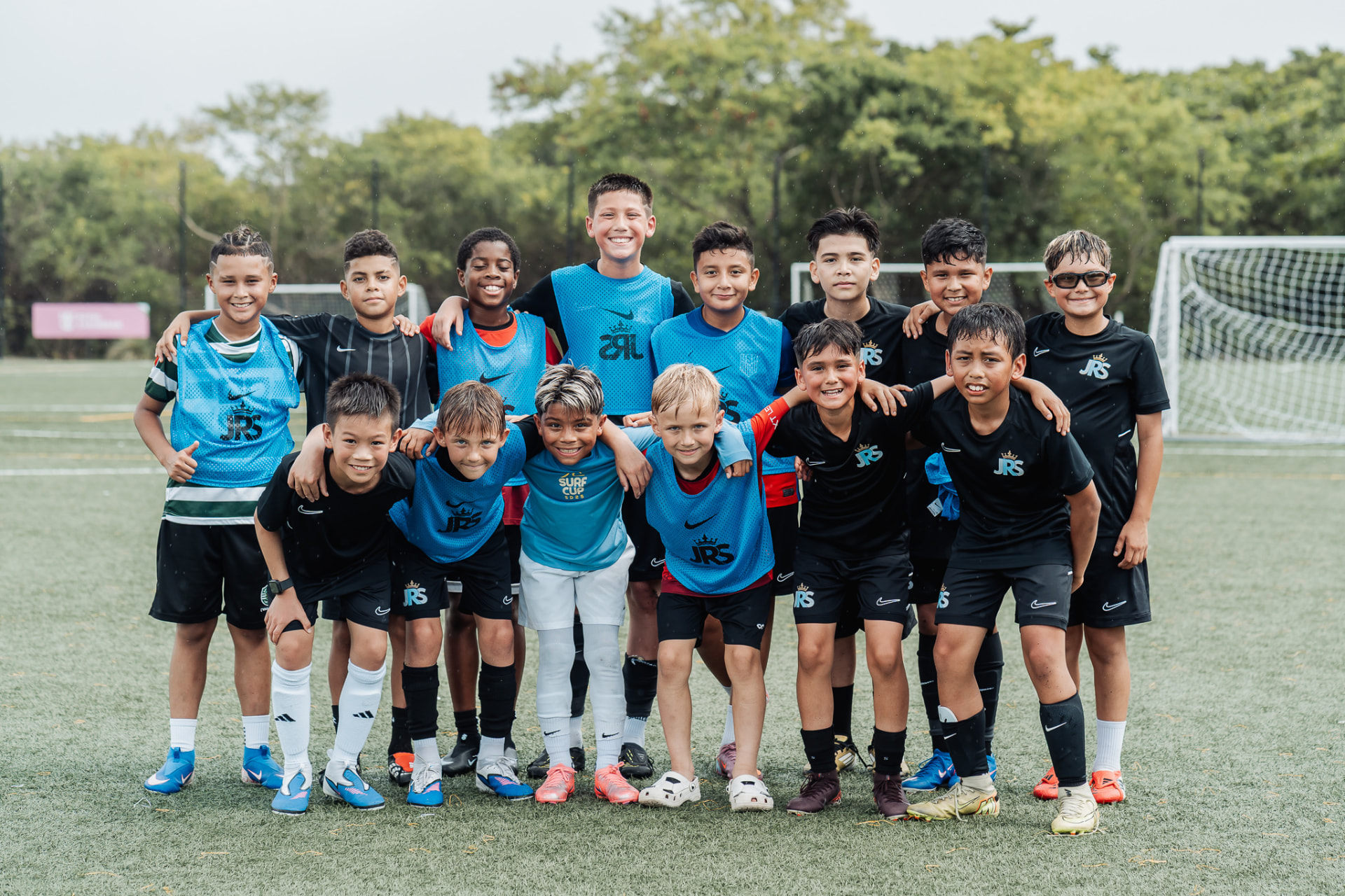 A JRS age-group squad poses together on a rain-soaked pitch during their tournament trip in Poland.