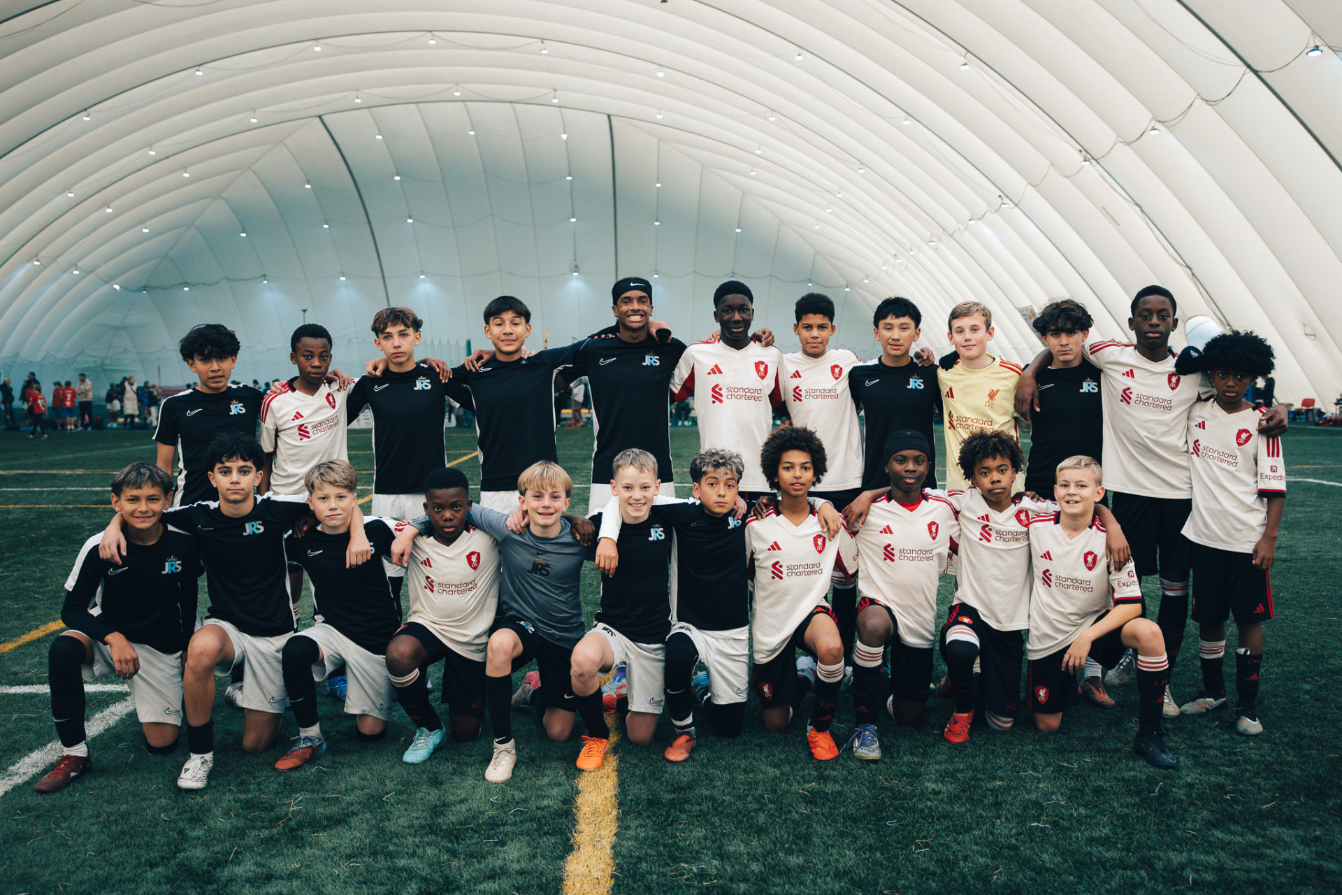 The JRS squad and coaches line up for a team photo under the covered pitch at the Number One Cup in Wrocław, Poland.