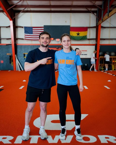 Coach and athlete on the turf in Gritworks shirts