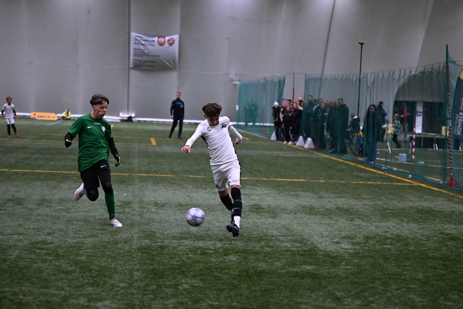 A JRS player breaks away with the ball while a defender chases him down the wing in Wrocław, Poland.
