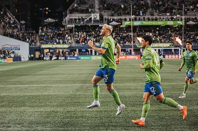 Seattle Sounders players run out onto the pitch in front of a packed night crowd