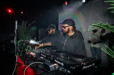 Two DJs work the decks under club lights