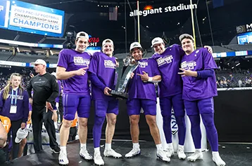 Players in purple champions shirts celebrate on a stage at Allegiant Stadium