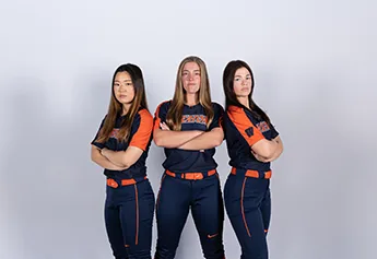 Three athletes in navy and orange stand with arms crossed on a white backdrop