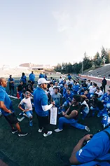 A youth team in blue sits together on a grass field