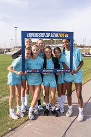 Young players in light blue pose with a tournament photo frame