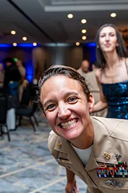 A Navy sailor smiles wide at a formal event