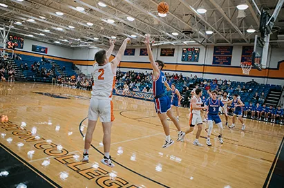 A basketball player rises for a jump shot in a college gym