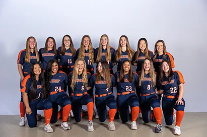 A women's team in navy and orange poses for a team photo