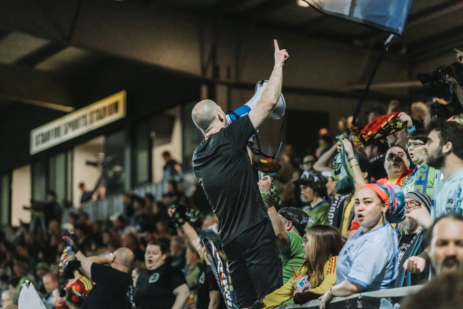 A supporter with a megaphone leads chants from the stands during a Sounders match.