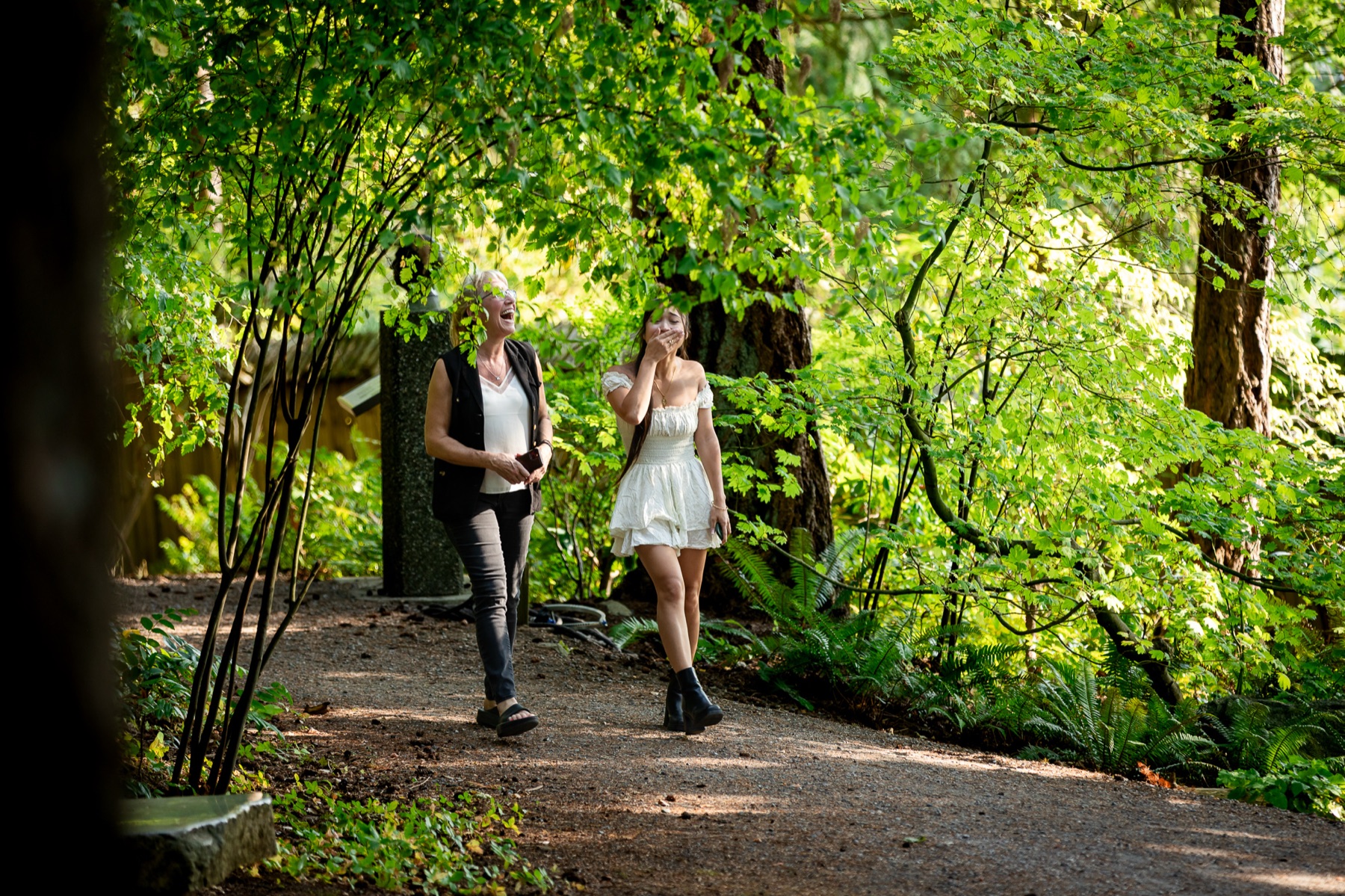 Jocelyn walks up a forest path in a white dress, hand over her mouth, moments before the proposal.