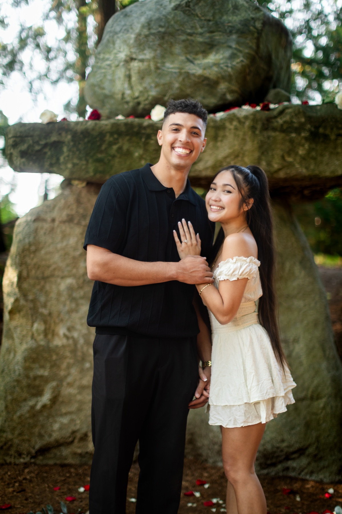 Trevor and Jocelyn hold each other and smile toward the camera in front of the stone arch.