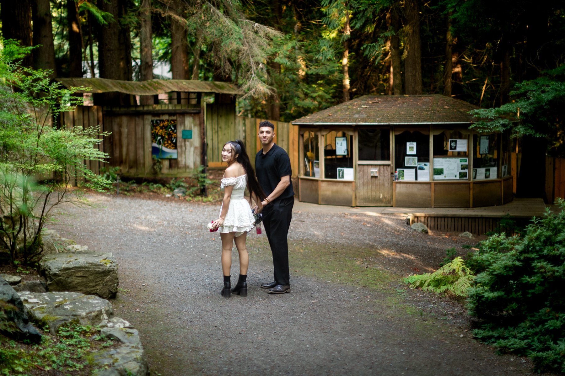 Trevor and Jocelyn glance back over their shoulders as they walk out of the garden hand in hand.