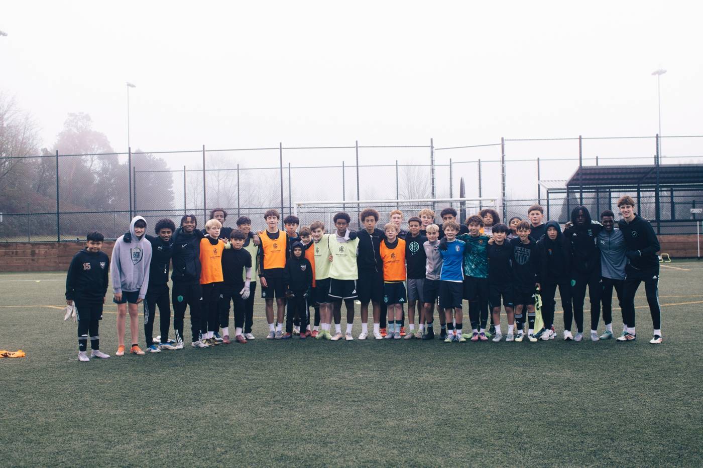 MV players and coaches lined up together on a foggy field after training