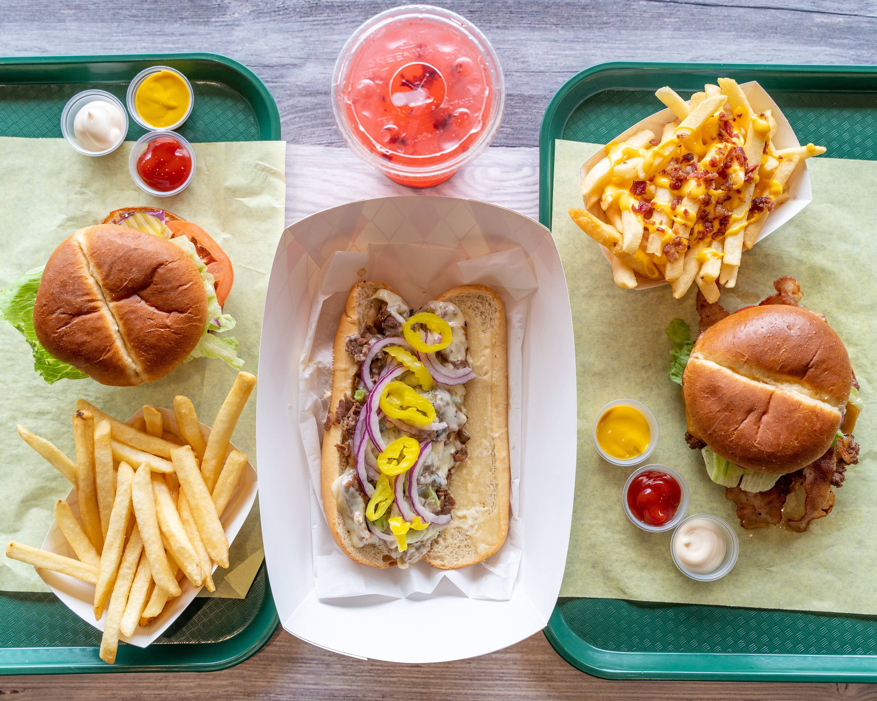 Burgers, a cheesesteak, regular fries, bacon cheese fries and a drink from Two Guys Burgers